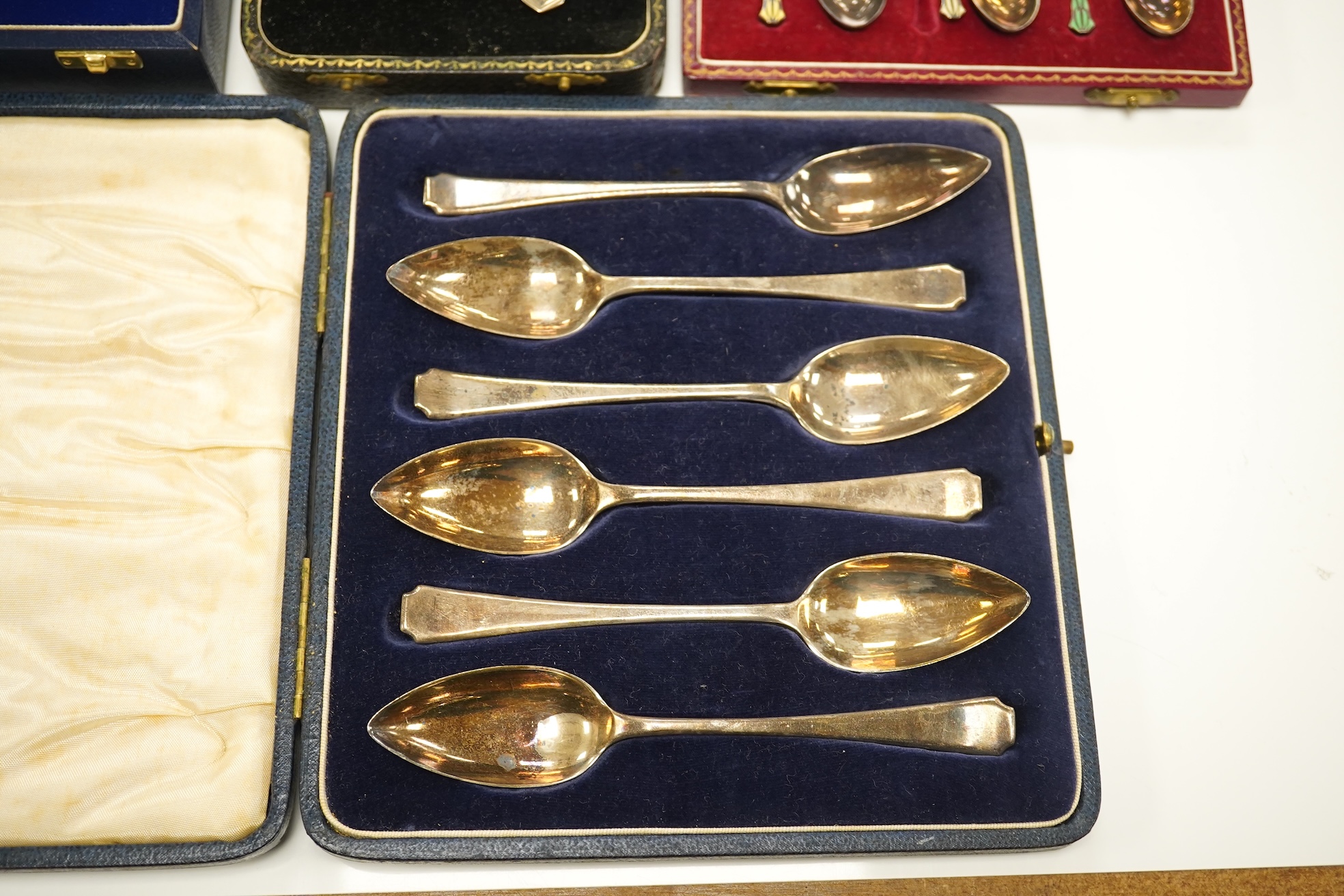 A set of six silver grapefruit spoons, Cooper Brothers & Sons, Sheffield, 1936, a modern pair of silver mounted dwarf candlesticks, a silver egg cup and spoon and a set of six silver gilt and enamelled coffee spoons, all